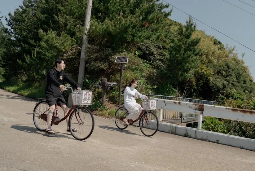 島の坂道を自転車で走るふたり