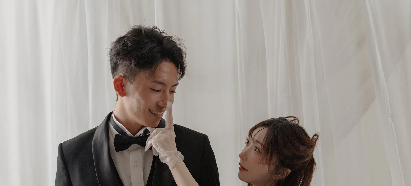 白い布を背に向かい合う新郎新婦